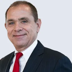 Kenneth R. Schuster, founding member of Schuster Law, in a navy pinstripe suit and red tie