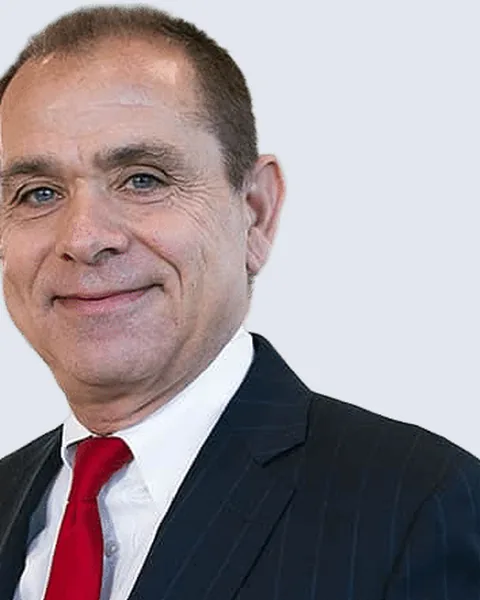 Kenneth R. Schuster, founding member of Schuster Law, in a navy pinstripe suit and red tie